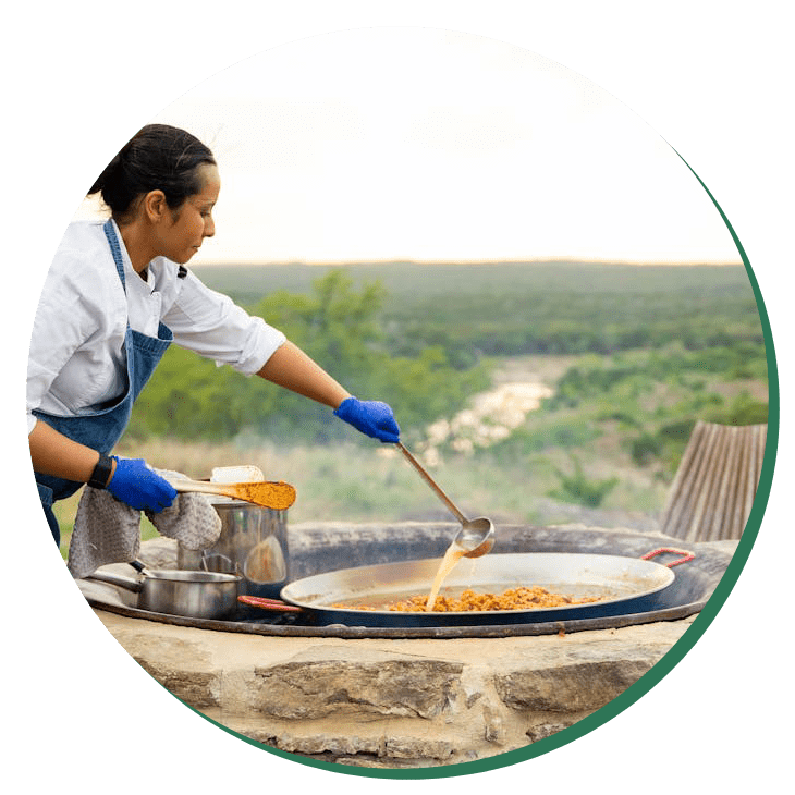 A woman cooking food on an outdoor grill.