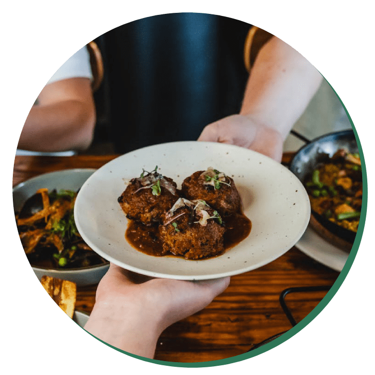 A person holding a plate of food on top of a table.