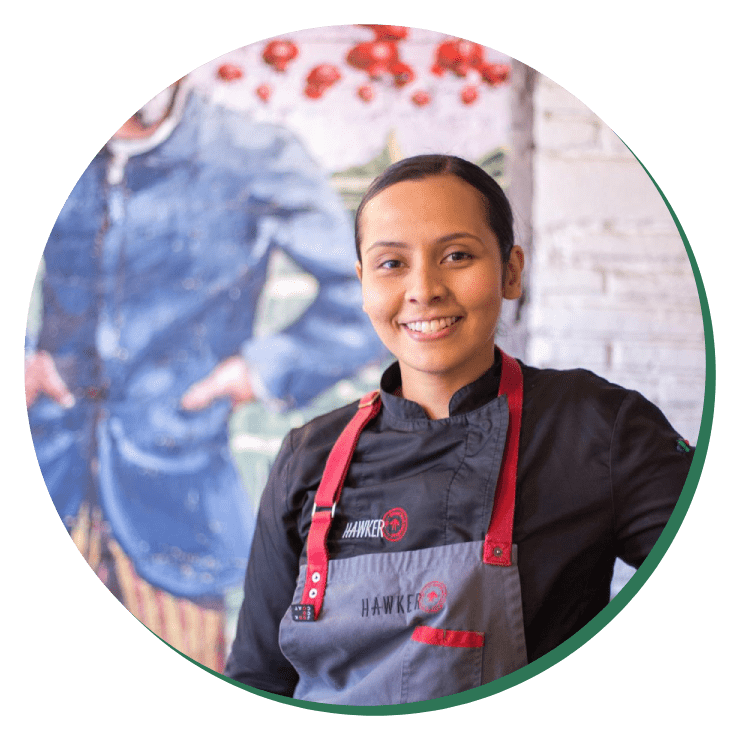 A woman in an apron standing next to a wall.