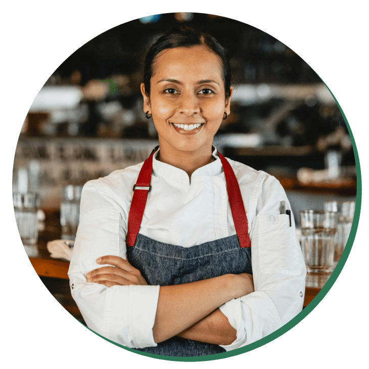 A woman in an apron standing with her arms crossed.